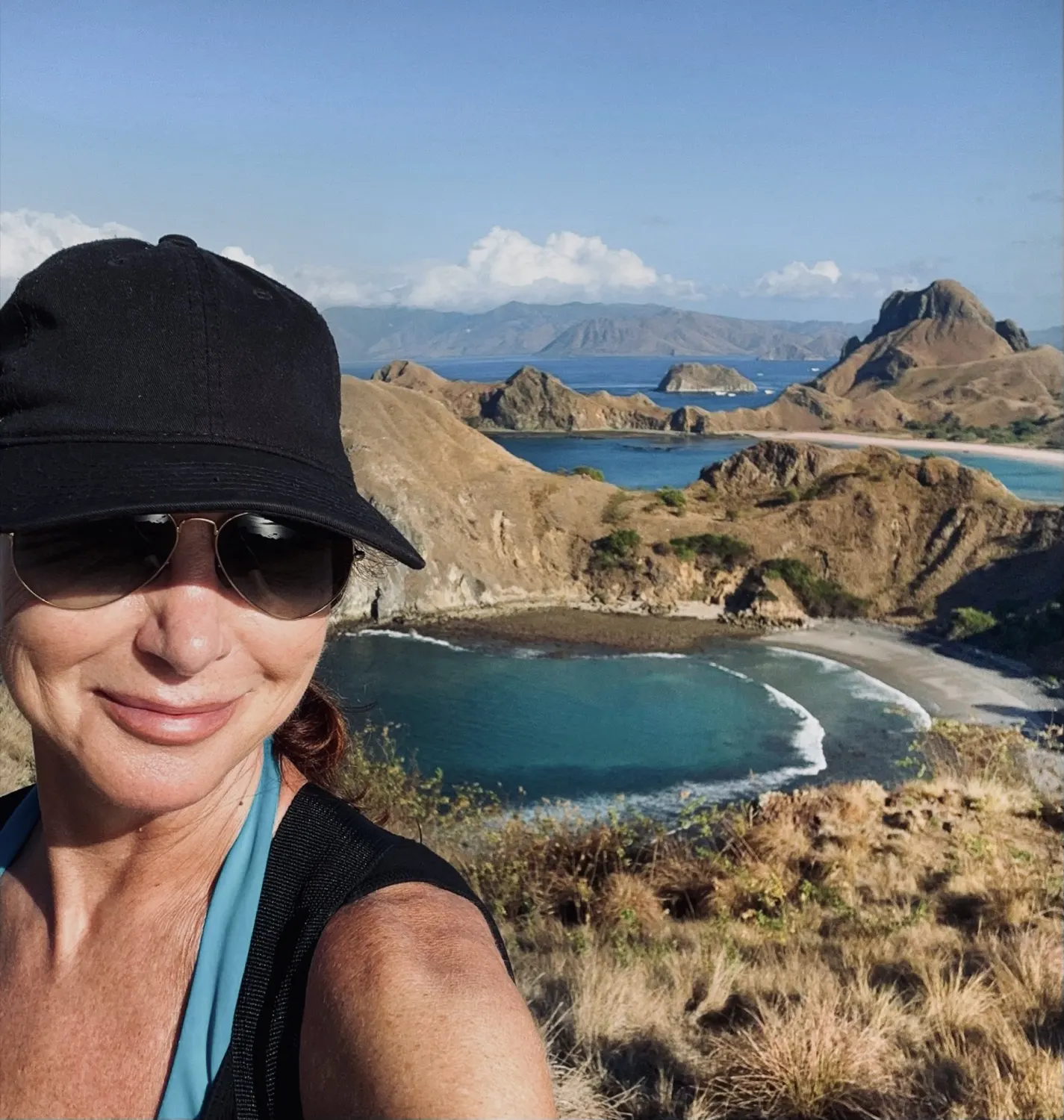 Monica looking out over a turquoise bay from a ridge on Padar Island, Indonesia