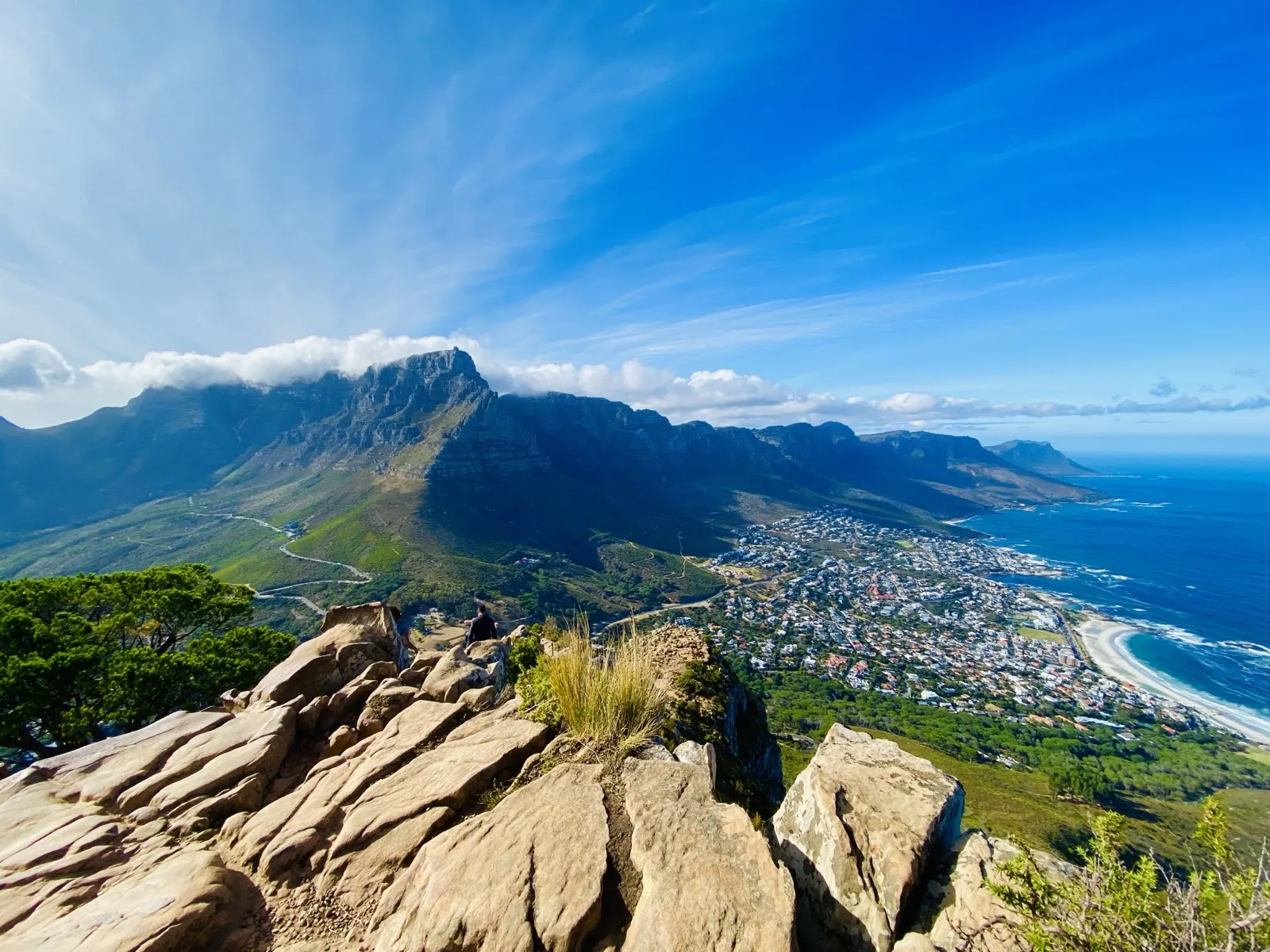 A ridge-top view over a mountain range falling away to the ocean, with a seaside town spread along the bay below